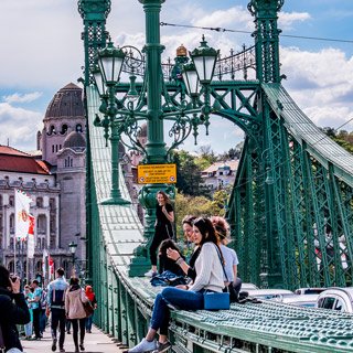 people sitting on Liberty Bridge in Budapest